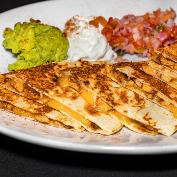 Cajun chicken quesadillas with melted cheese, served with guacamole, sour cream, and pico de gallo.