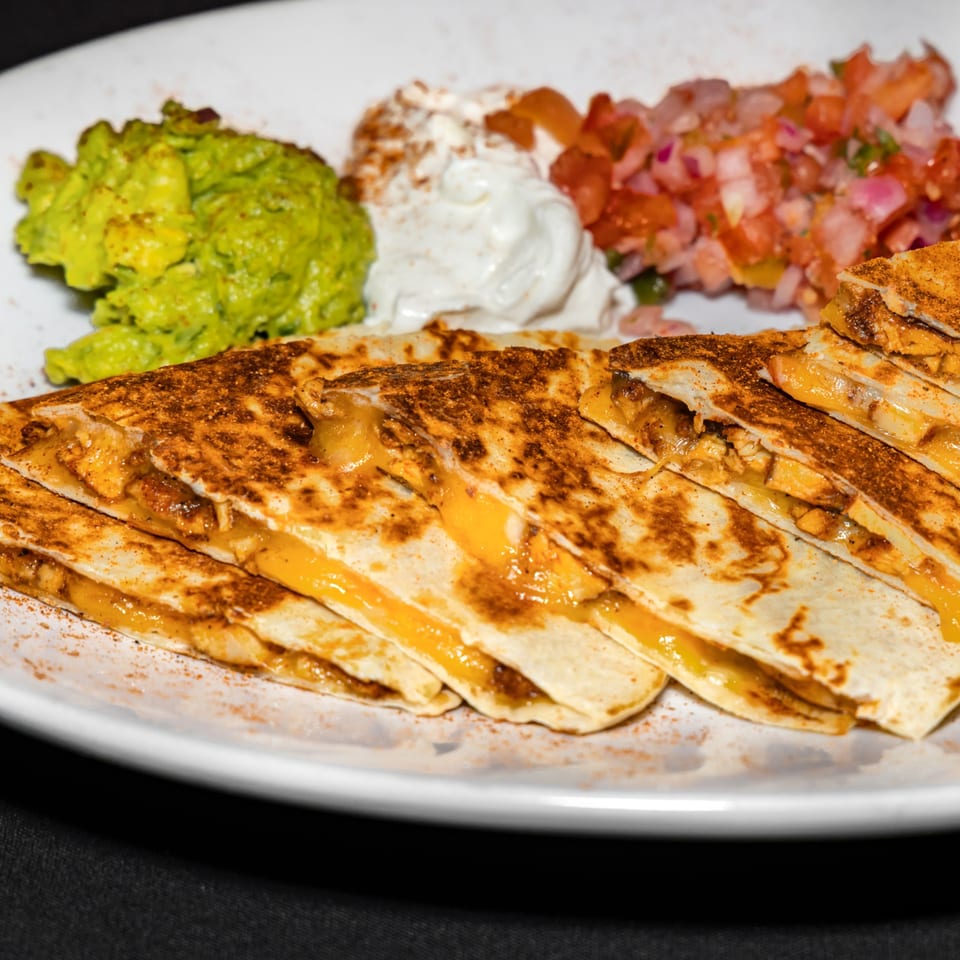 Cajun chicken quesadillas with melted cheese, served with guacamole, sour cream, and pico de gallo.