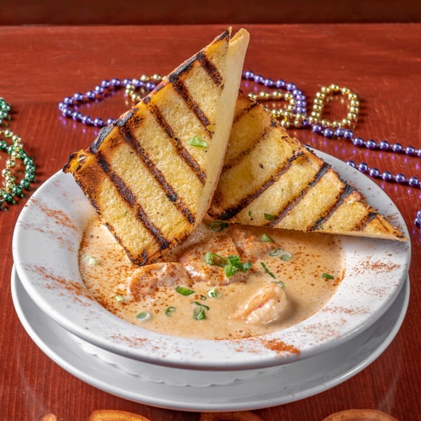 Cajun shrimp etouffee with grilled bread, garnished with green onions and Mardi Gras beads.